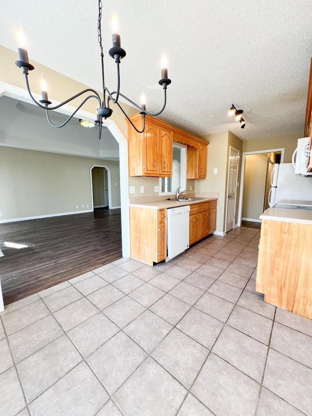 kitchen with white appliances, arched walkways, light countertops, and light tile patterned flooring