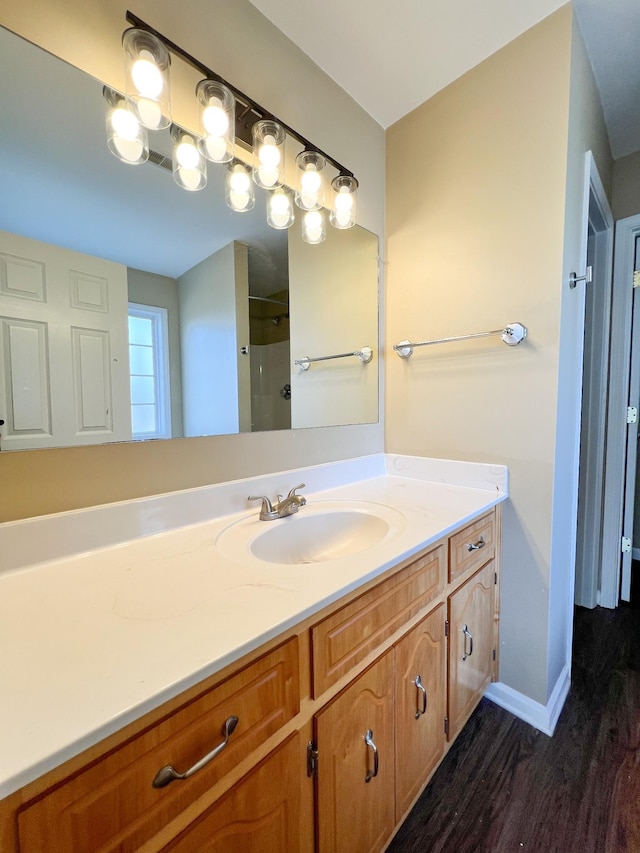 full bath featuring walk in shower, wood finished floors, vanity, and baseboards