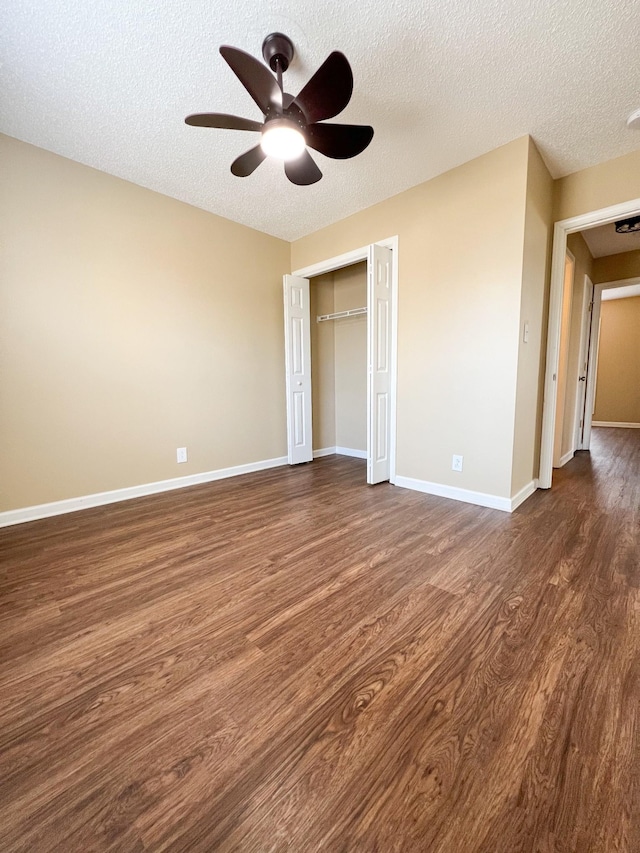 unfurnished bedroom featuring a textured ceiling, a closet, baseboards, and dark wood-style flooring