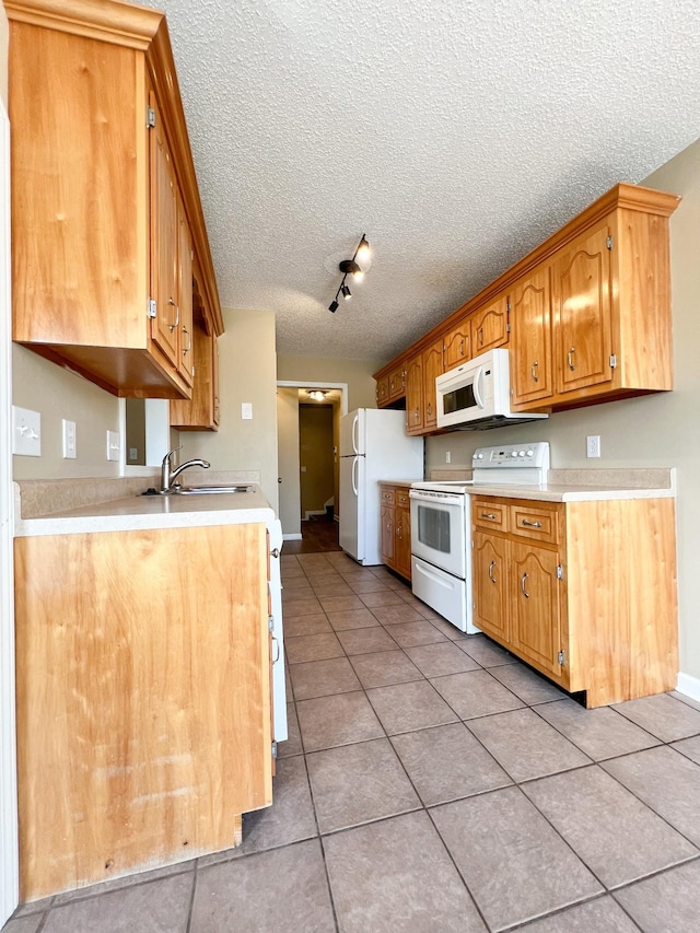 kitchen featuring light tile patterned floors, light countertops, white appliances, and a sink