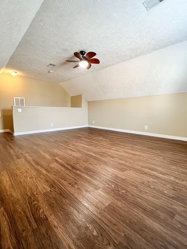 additional living space featuring baseboards, visible vents, vaulted ceiling, and wood finished floors