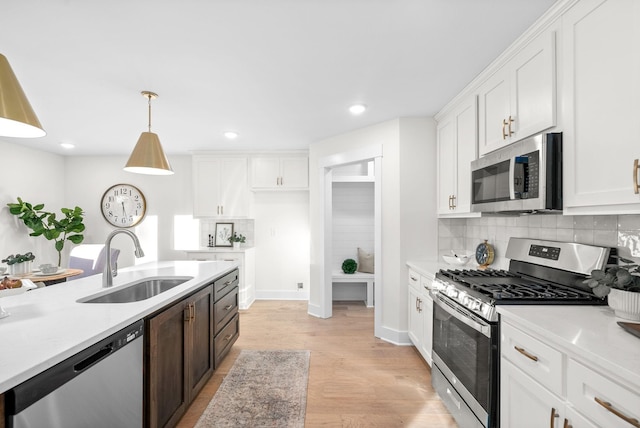 kitchen with white cabinetry, appliances with stainless steel finishes, light countertops, and decorative light fixtures