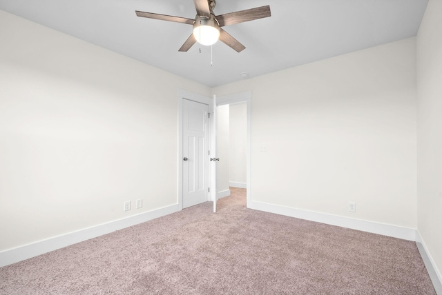 carpeted empty room with a ceiling fan and baseboards