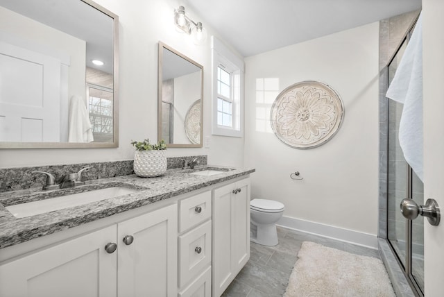 bathroom with a stall shower, a sink, baseboards, and double vanity