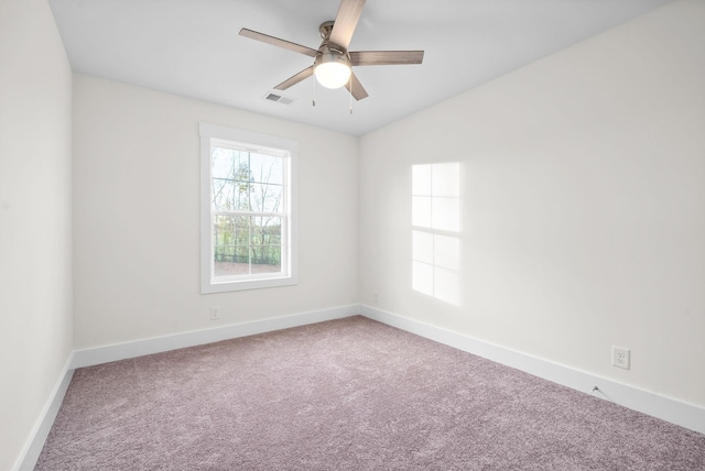 empty room with carpet floors, visible vents, ceiling fan, and baseboards