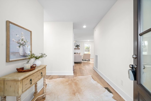 hall featuring light wood finished floors, recessed lighting, visible vents, and baseboards