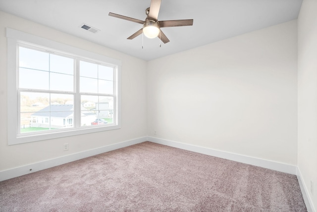 carpeted empty room featuring visible vents, ceiling fan, and baseboards