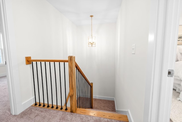 stairs featuring carpet floors, a notable chandelier, and baseboards