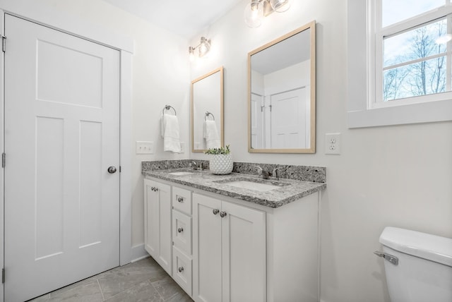 full bath with a sink, toilet, and double vanity