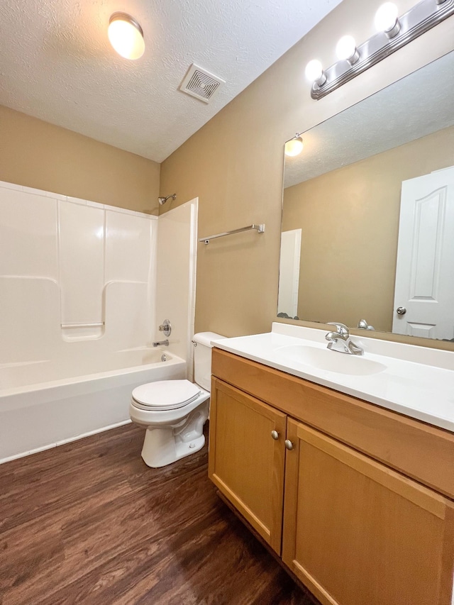 bathroom with visible vents, toilet, washtub / shower combination, a textured ceiling, and wood finished floors