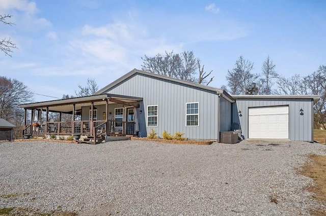 view of front of house with an attached garage, a porch, and gravel driveway