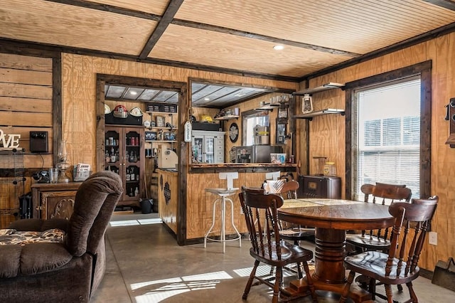dining area with concrete flooring, wood ceiling, wooden walls, and a dry bar