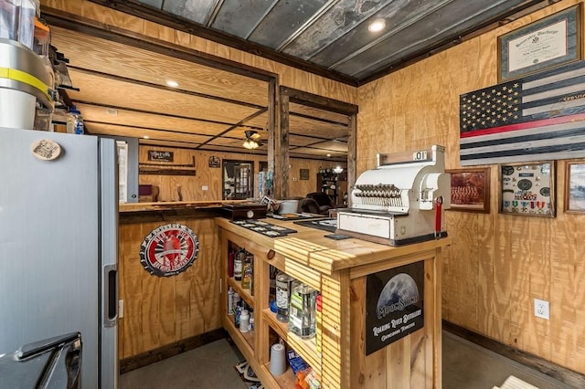 kitchen with a ceiling fan, freestanding refrigerator, and wooden walls