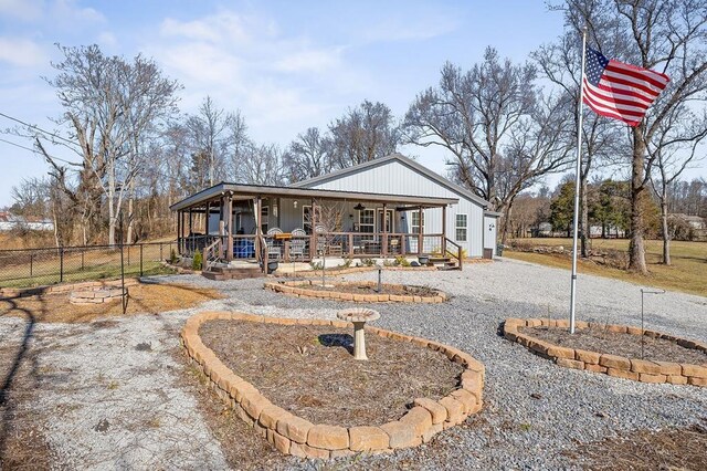 view of front of property with a porch, fence, and a fire pit