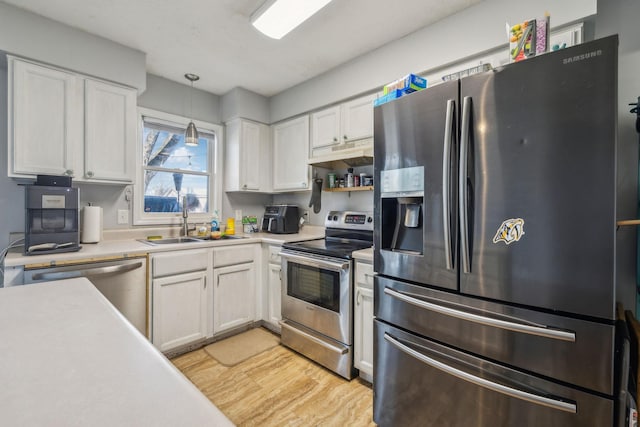 kitchen featuring stainless steel appliances, light countertops, white cabinetry, and pendant lighting