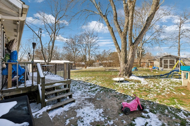 snowy yard with a playground, an outdoor structure, and a deck