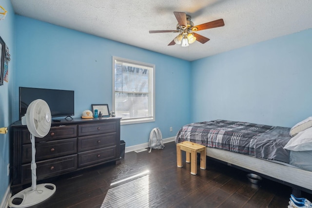 bedroom with dark wood-style floors, ceiling fan, baseboards, and a textured ceiling