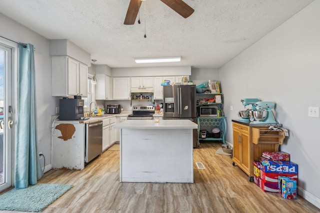 kitchen with stainless steel appliances, light countertops, white cabinets, and a sink