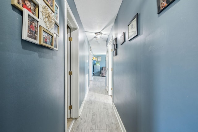 corridor featuring light wood-style flooring and baseboards