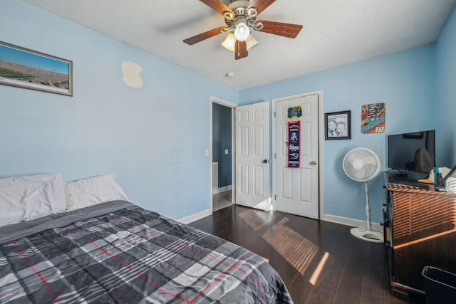 bedroom with ceiling fan, baseboards, dark wood finished floors, and a textured ceiling