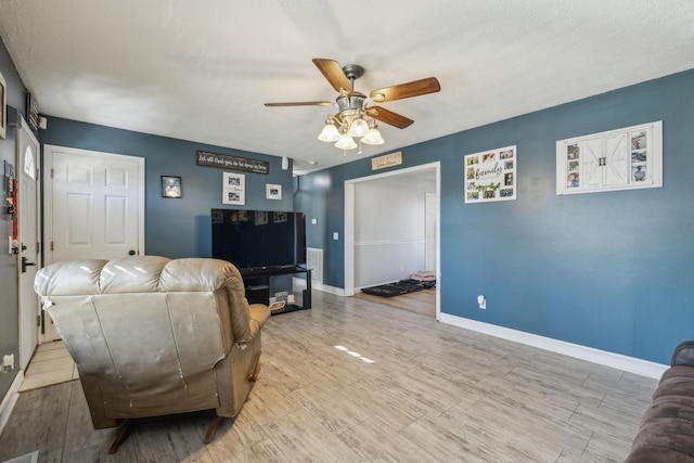 living room with ceiling fan, light wood-style flooring, and baseboards