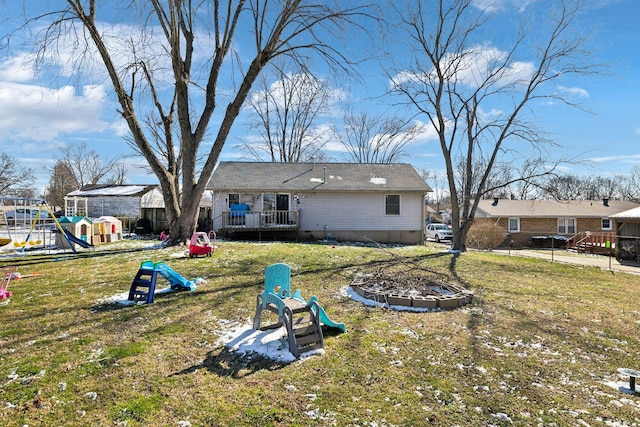 rear view of property with a playground, a yard, and a deck