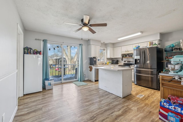 kitchen featuring ceiling fan, a kitchen island, white cabinetry, light countertops, and appliances with stainless steel finishes