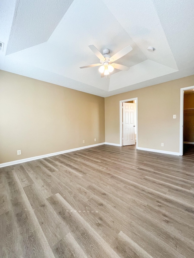 spare room featuring ceiling fan, baseboards, a raised ceiling, and wood finished floors