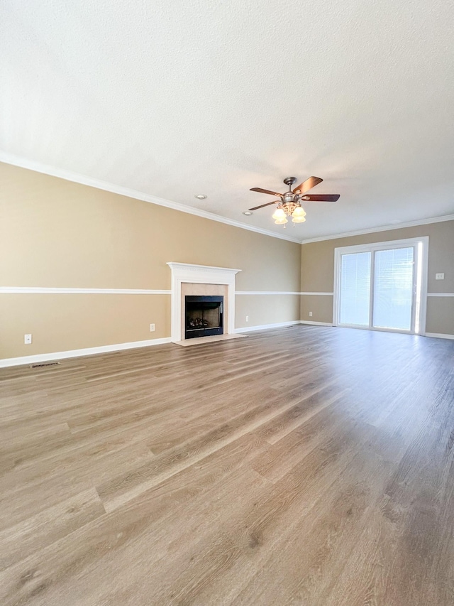 unfurnished living room featuring ornamental molding, light wood-type flooring, and a fireplace with flush hearth