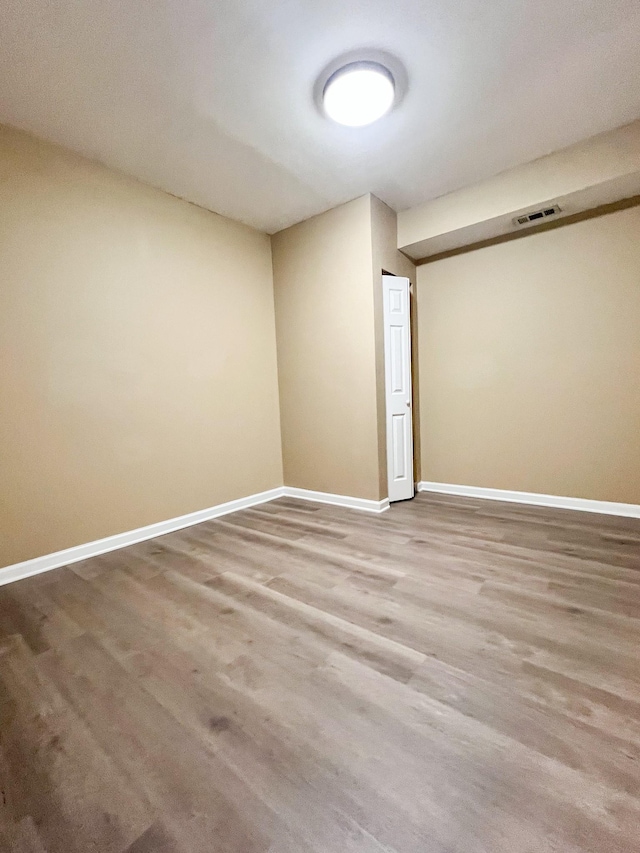 empty room featuring visible vents, baseboards, and wood finished floors