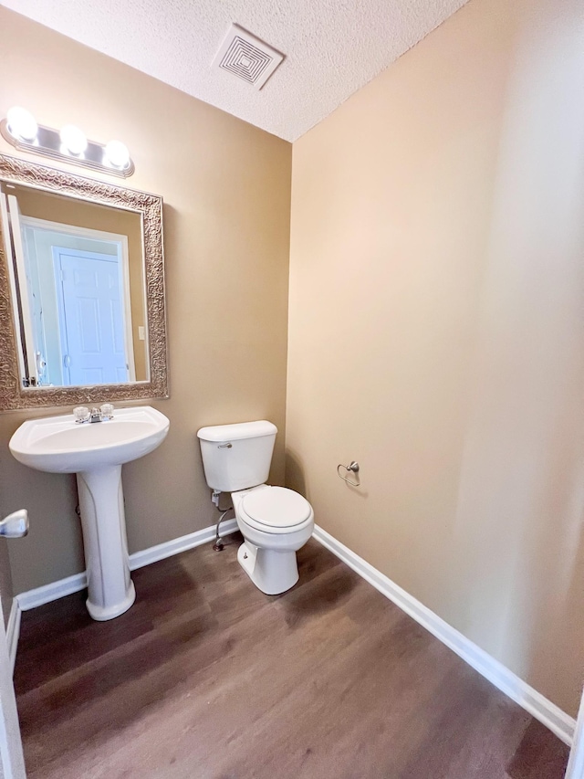 bathroom with visible vents, toilet, baseboards, and wood finished floors