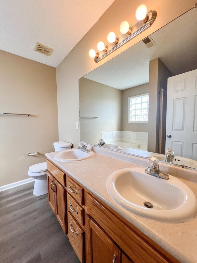 bathroom with toilet, a sink, visible vents, and a bath