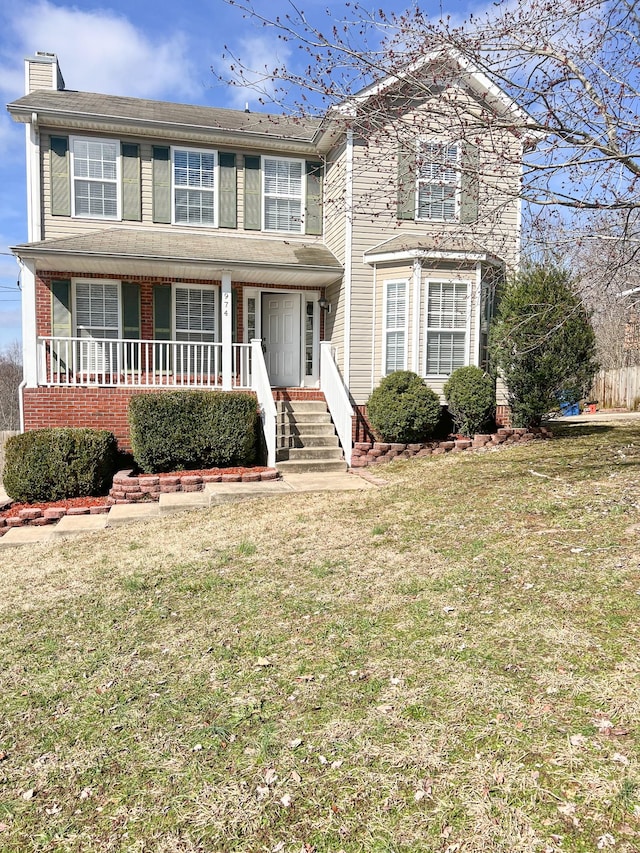 traditional-style home with a chimney, a porch, and a front yard