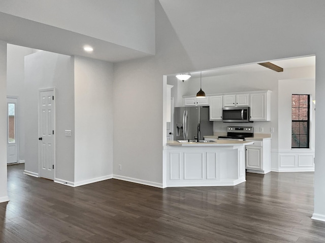 kitchen with pendant lighting, stainless steel appliances, light countertops, dark wood-type flooring, and white cabinets