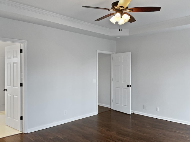 empty room featuring ceiling fan, dark wood-type flooring, ornamental molding, and baseboards