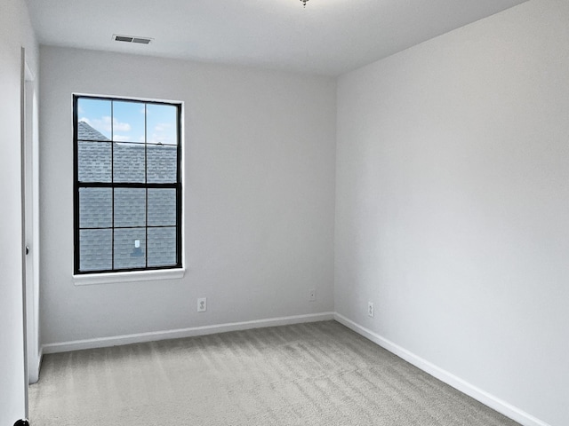 spare room with light colored carpet, visible vents, and baseboards