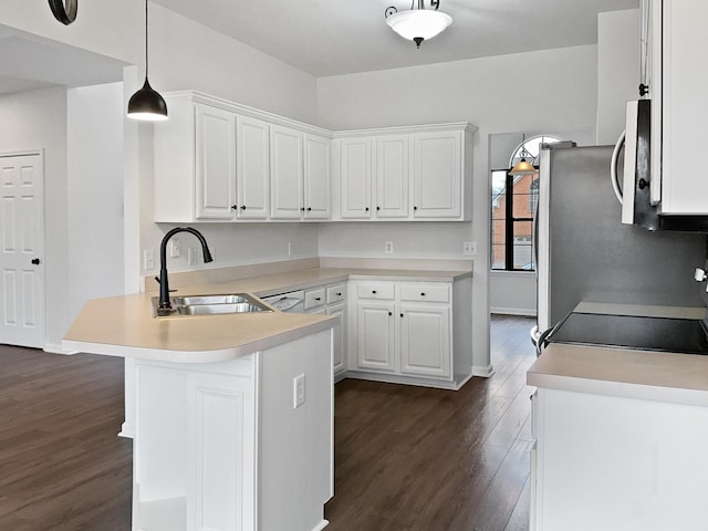 kitchen featuring white cabinets, a peninsula, light countertops, pendant lighting, and a sink