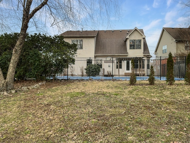 rear view of property featuring fence and a lawn