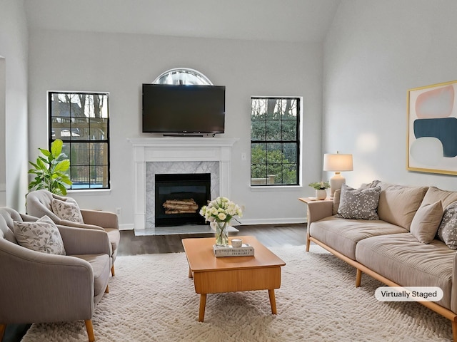 living area with a fireplace, baseboards, and wood finished floors