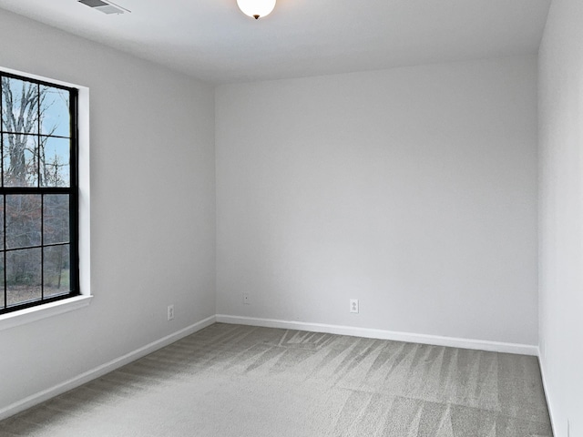 carpeted spare room with visible vents and baseboards