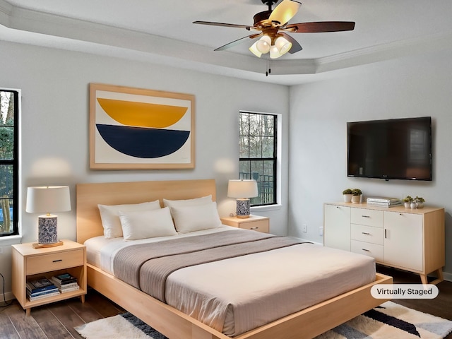 bedroom with dark wood-type flooring, a tray ceiling, and a ceiling fan