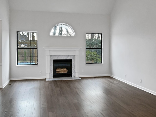 unfurnished living room featuring a fireplace, dark wood finished floors, and baseboards