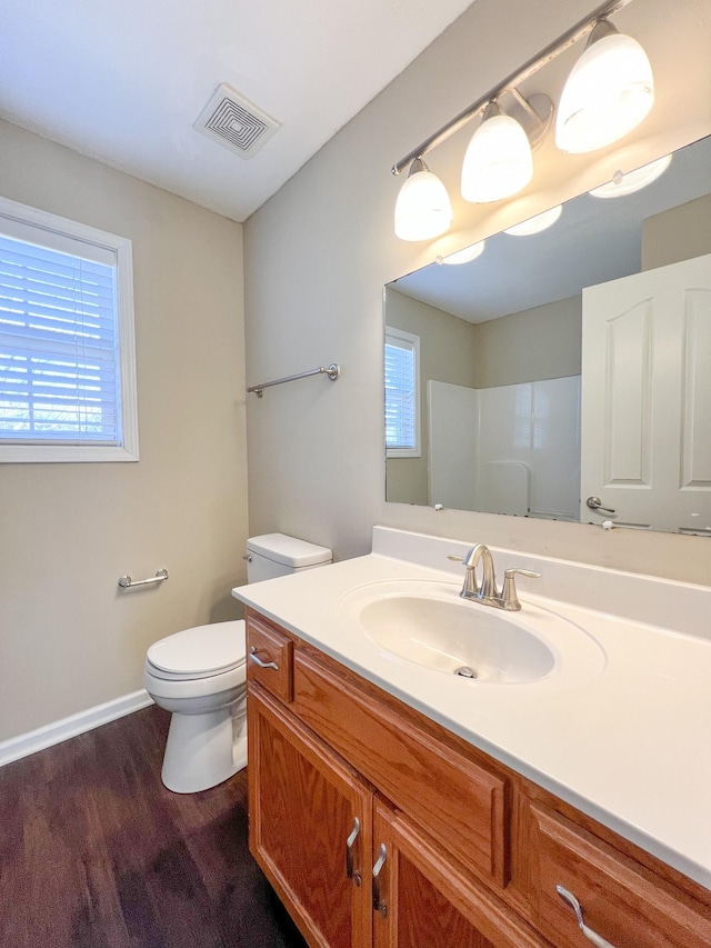 bathroom featuring a shower, visible vents, toilet, vanity, and wood finished floors