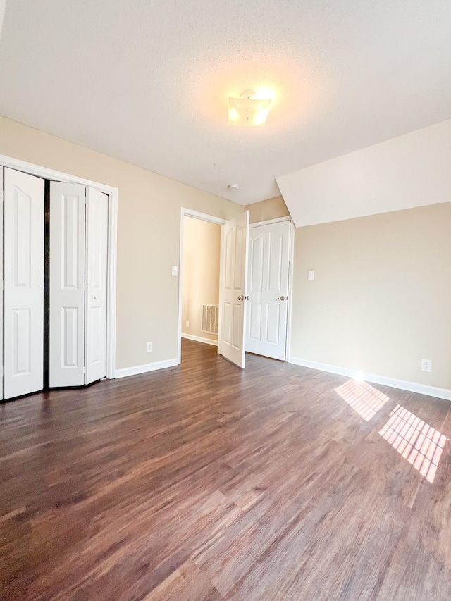 unfurnished bedroom featuring baseboards, a closet, visible vents, and dark wood-type flooring