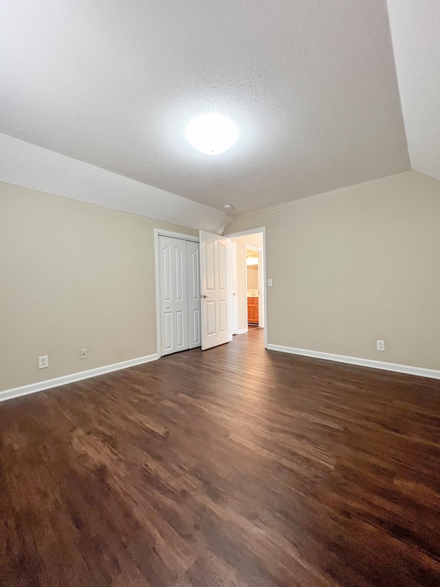 interior space with lofted ceiling, dark wood-style flooring, and baseboards