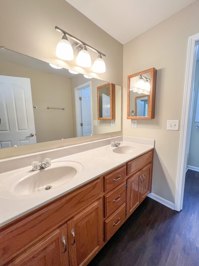 bathroom featuring double vanity, baseboards, a sink, and wood finished floors