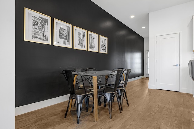 dining room featuring an accent wall, recessed lighting, baseboards, and light wood finished floors