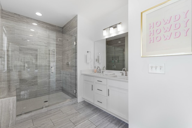 bathroom featuring double vanity, a stall shower, and a sink