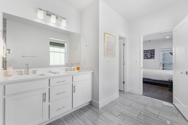 ensuite bathroom featuring wood tiled floor, a sink, ensuite bath, and double vanity