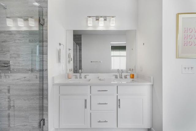 bathroom with a sink, a shower stall, and double vanity